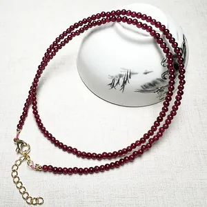 Garnet beaded necklace with adjustable gold clasp on a traditional ceramic bowl