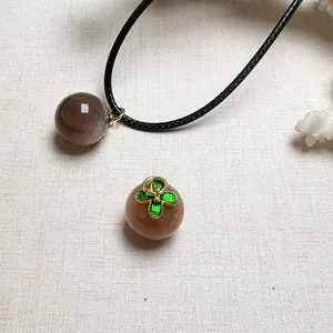 Detailed macro of orange sunstone crystal pendants with green clover enamel accents