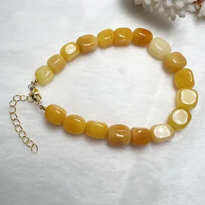 Dettaglio di un bracciale con perle di pietre naturali gialle con chiusura a moschettone dorata