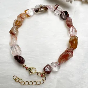 Dettaglio di un bracciale con cristalli naturali multicolore e chiusura a moschettone dorata