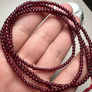 Macro detail of natural deep red garnet bead bracelet with traditional red cord knot