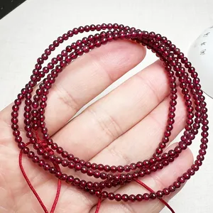 Macro shot of 3-4mm garnet beads wrap bracelet with deep red luster on a textured background