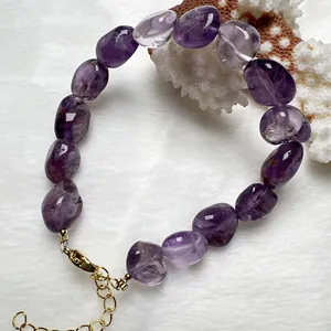 Dettaglio del bracciale di ametista con perle irregolari e chiusura dorata su pelliccia