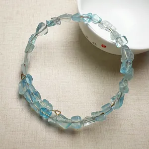 Détail du bracelet en cristal brut bleu clair avec un fil doré ajustable en spirale