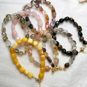 Dettaglio di bracciali in cristalli naturali con chiusure a moschettone dorate e catene