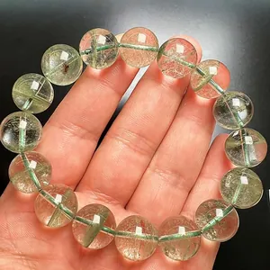 Primer plano de pulsera de cuarzo fantasma verde natural con cuentas de cristal en una mano