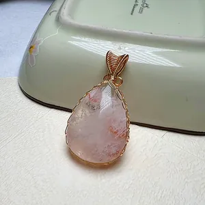 Detail eines tropfenförmigen rosa Kristallanhängers mit handgefertigter Golddrahtwicklung