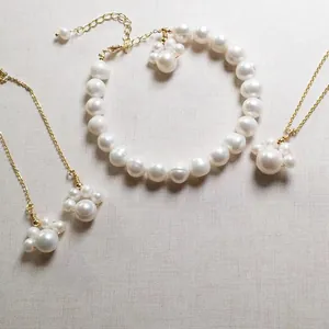 Detail of freshwater pearl jewelry set featuring golden cat claw pendants on linen