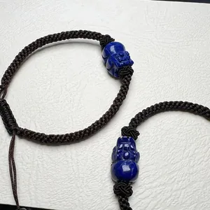Macro shot of hand-woven cord bracelets featuring blue lapis lazuli Pixiu carvings