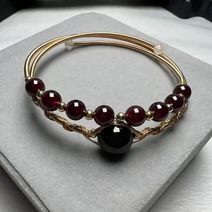 Macro view of woven gold wire bracelet with red garnet beads and intricate craft details