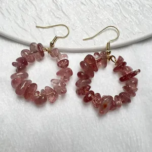 Orecchini a cerchio dorati fatti a mano con pietre di quarzo fragola su sfondo bianco