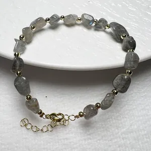Detailaufnahme von Labradorit-Steinen auf Armband mit goldenem Karabinerverschluss