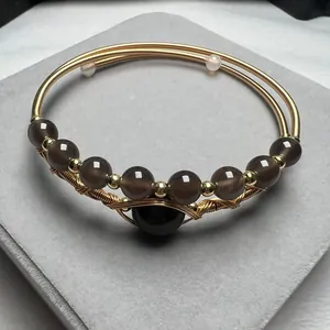 Close-up of handmade 14K gold filled wire bracelet with brown agate and garnet beads