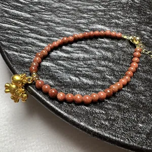 Rodbruine goudsteen kralenarmband met een gouden paardenhanger en een verstelbare sluiting