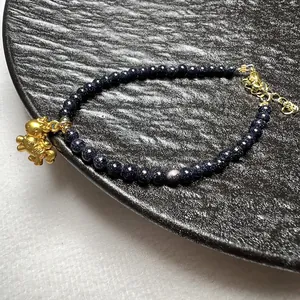 Kralenarmband van blauwe zandsteen met gouden astronaut-hanger en verstelbare karabijnsluiting