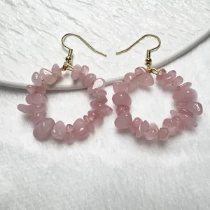 Primo piano di orecchini a cerchio in quarzo rosa con ganci dorati su piatto bianco