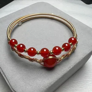 Detailed macro view of 14K gold-filled wire-wrapped cuff with red agate beads