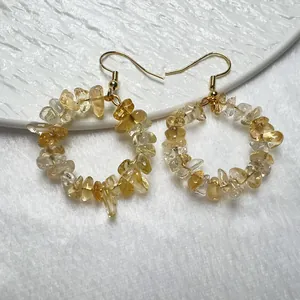 Dettaglio di orecchini pendenti in citrina gialla con ganci dorati su sfondo bianco