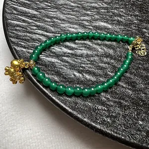 Detailopname van groene agaat kralenarmband met een gouden dierlijk hangertje