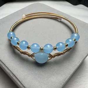 Handcrafted 14K gold filled bangle with nine light blue agate beads on velvet stand