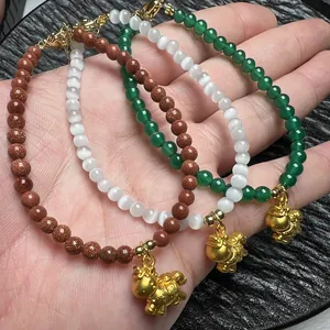 Detailopname van kralenarmbanden van groene agaat, kattenoogsteen en goudsteen met paardhangers