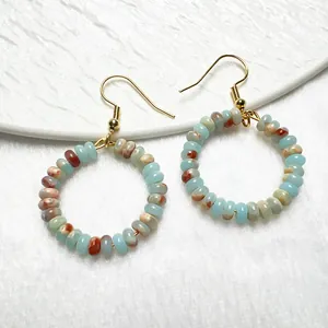 Dettaglio di orecchini boho dorati con perle di quarzo e granato naturale irregolare