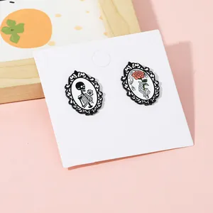 Nahaufnahme gotischer Emaille-Pins mit Totenkopf und Knochenhand mit roter Rose
