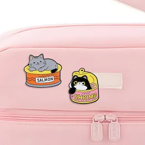 Détail des broches chat en émail saumon et crevette sur une pochette rose à fermeture