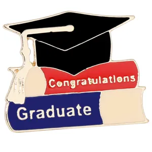 Close-up of graduation enamel pin featuring a black cap and stack of books detail