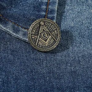 Macro shot of vintage bronze Freemasonry badge with compass and square on denim fabric