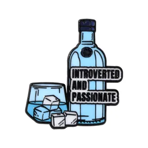 Dettaglio della spilla in smalto con bottiglia blu e bicchiere con testo introverted e passionate