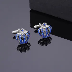 Dettaglio macro di gemelli a corona d'argento con cristalli blu su superficie a specchio