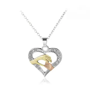 Detail of heart pendant with gold parent and child hands holding each other