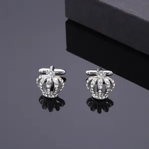 Gemelli a corona d'argento con strass scintillanti su un elegante sfondo nero riflettente
