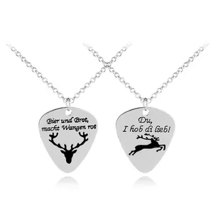 Detail of silver guitar pick pendants with deer engravings and German inscriptions