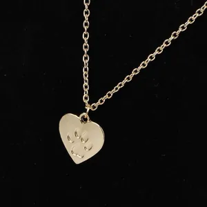 Macro view of golden heart pendant featuring engraved pet paw print on link chain