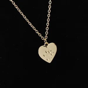 Close-up of golden heart pendant with a pet paw print on a black velvet background