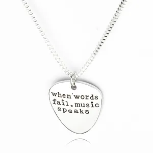 Macro detail of silver guitar pick necklace with when words fail music speaks engraving