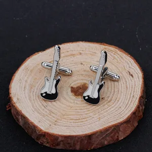 Détail des boutons de manchette guitare électrique en émail noir sur socle en bois brut