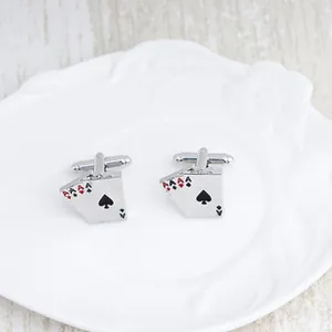 Detail shot of silver poker Ace cards cufflinks on a white decorative plate