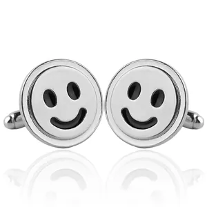 Detailopname van gepolijste zilveren smiley manchetknopen met zwarte details op wit