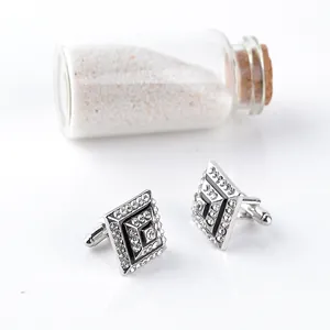 Close-up of square silver cufflinks with sparkling rhinestones and black enamel accents