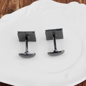 Gemelli da polso quadrati canna di fucile su ceramica bianca e tavolo in legno