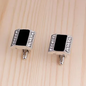 Elegant square silver cufflinks with black center and sparkling rhinestones on wood base