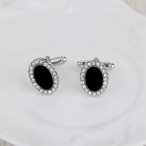 Détail de boutons de manchette argentés avec insert ovale noir et cristaux scintillants