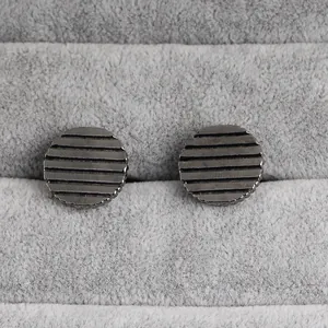 Détail macro de boutons de manchette ronds rayés pour hommes sur un présentoir en velours