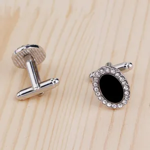 Gros plan de boutons de manchette argentés avec insert noir et bordure de cristaux brillants
