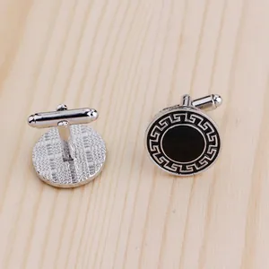 Détail de boutons de manchette ronds argent et noir avec motif grec sur bois