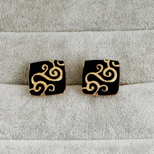 Boutons de manchette carrés noirs et dorés avec motif floral sur présentoir en velours