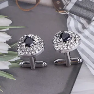 Close-up of silver heart cufflinks with black stone and rhinestones on a tray